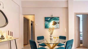 Uma sala de jantar moderna com mesa de vidro, cadeiras verde-água e um quadro na parede.