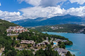 A resort with multiple buildings, a swimming pool, and a lake with mountains in the background. - Mobile Homes for 4 People With Lake View in Residence L'ecrin du Lac, Chorges (Chorges)