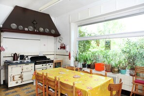 Een keuken met een fornuis, oven en een eettafel met stoelen.