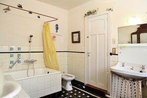 A bathroom with a bathtub, toilet, sink, and a showerhead. - Spacious 11-bed Family Retreat (Ruiselede)