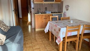 A compact kitchen with wooden cabinets, a microwave, and a small dining area with a table and chairs. - Apartment in Chatel Near Cable Car (Chatel)
