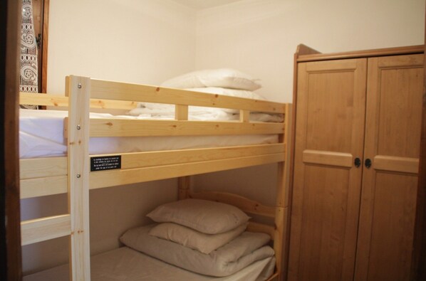 A bunk bed with a wooden headboard, a lower bunk with pillows, and a wardrobe with two doors. - Apartment in Chatel Near Cable Car (Chatel)
