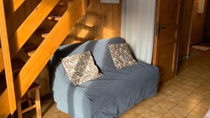 A wooden staircase, a sofa with patterned cushions, and a door with a towel hanging on it. - Apartment in Chatel Near Cable Car (Chatel)