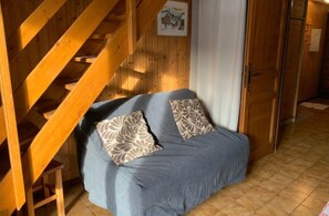A wooden staircase, a sofa with patterned cushions, and a door with a towel hanging on it. - Apartment in Chatel Near Cable Car (Chatel)