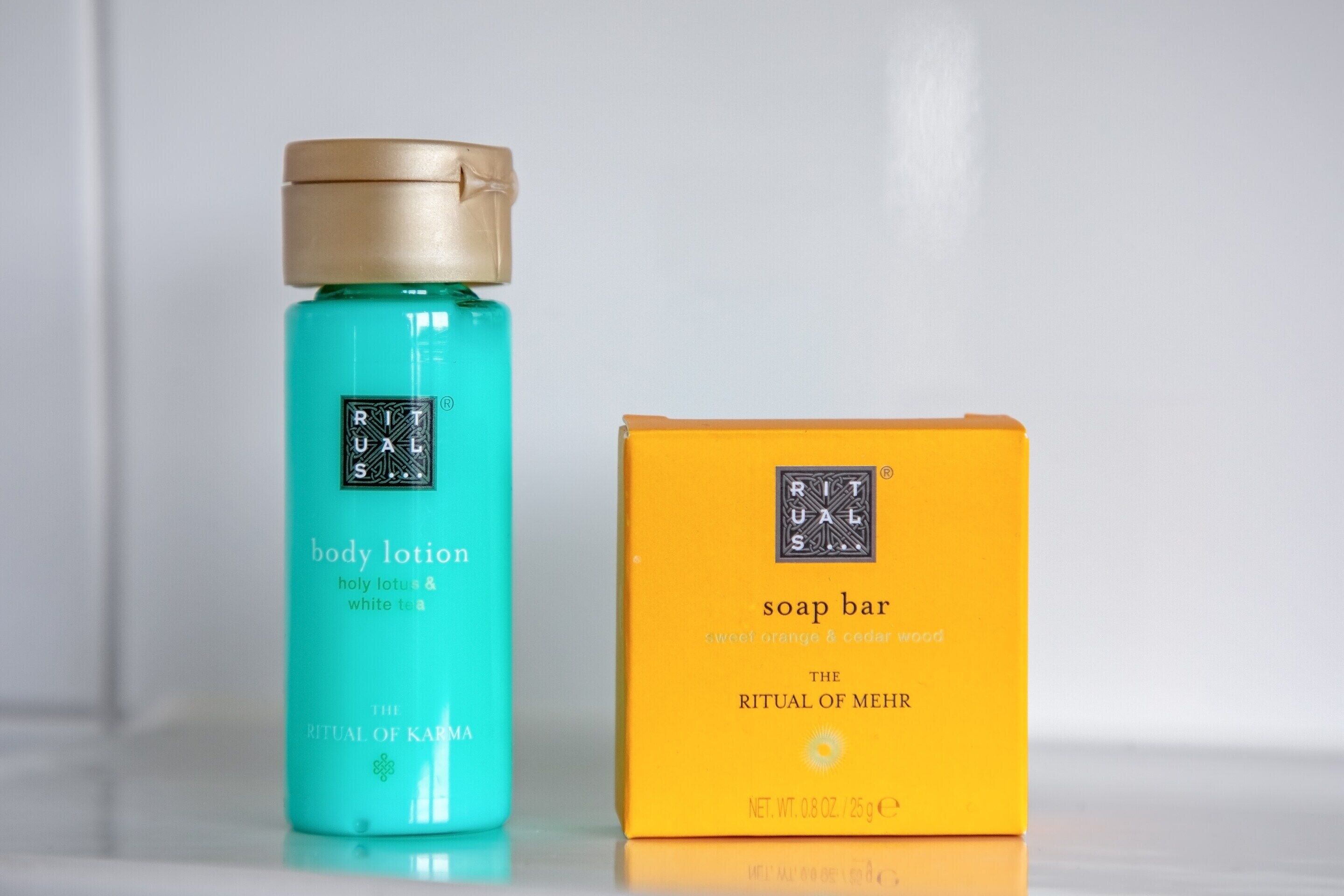 Two products, a body lotion and a soap bar, with labels indicating 'RITUAL OF MEHR' and 'THE RITUAL OF KARMA'.