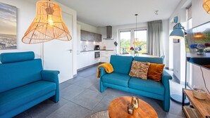 A modern living room with a sofa, coffee table, and hanging light fixture. - Stylish Texel Escape With Spa (Den Burg)