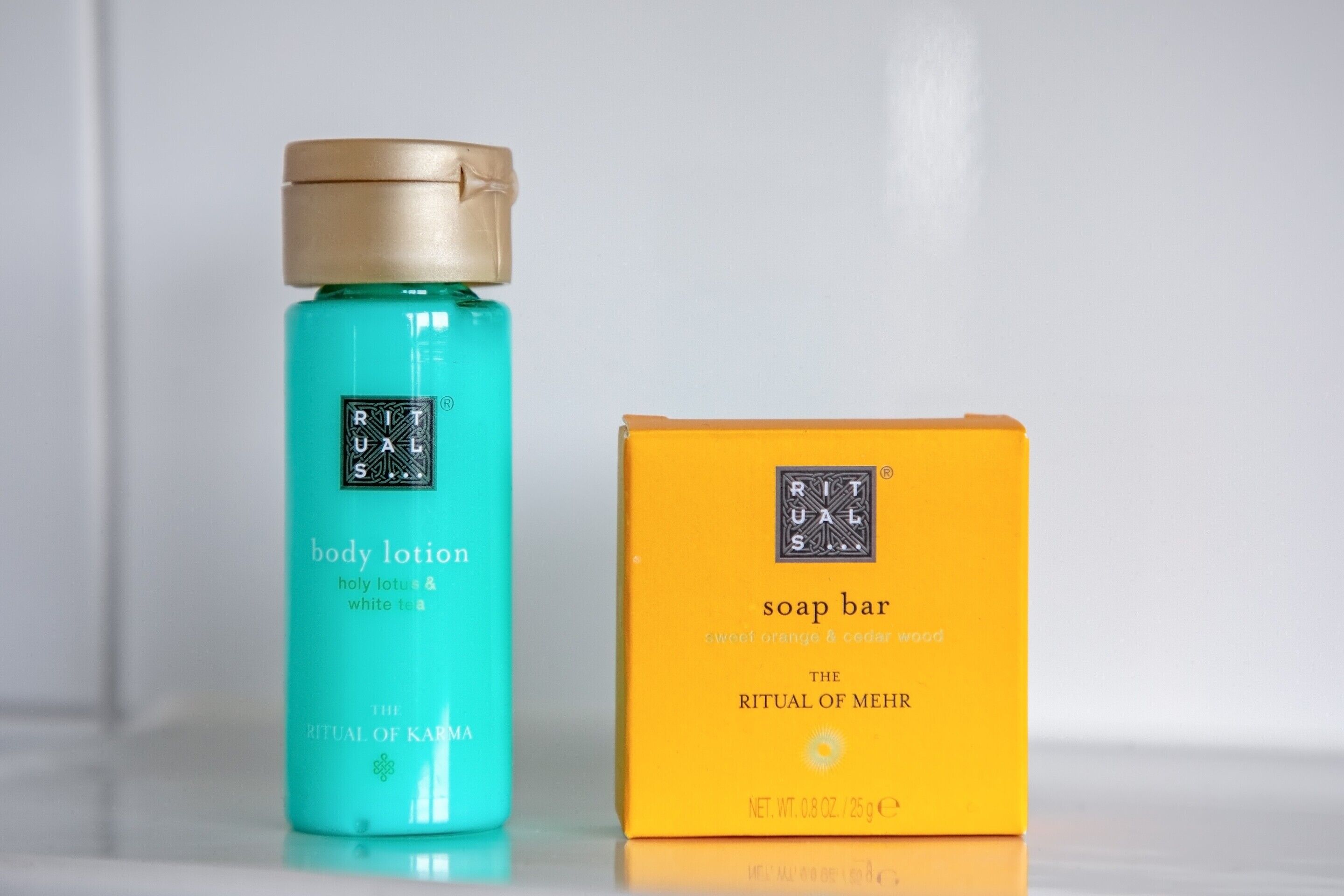 A body lotion and a soap bar with labels indicating 'RITUAL OF MEHR' and 'THE RITUAL OF KARMA'.