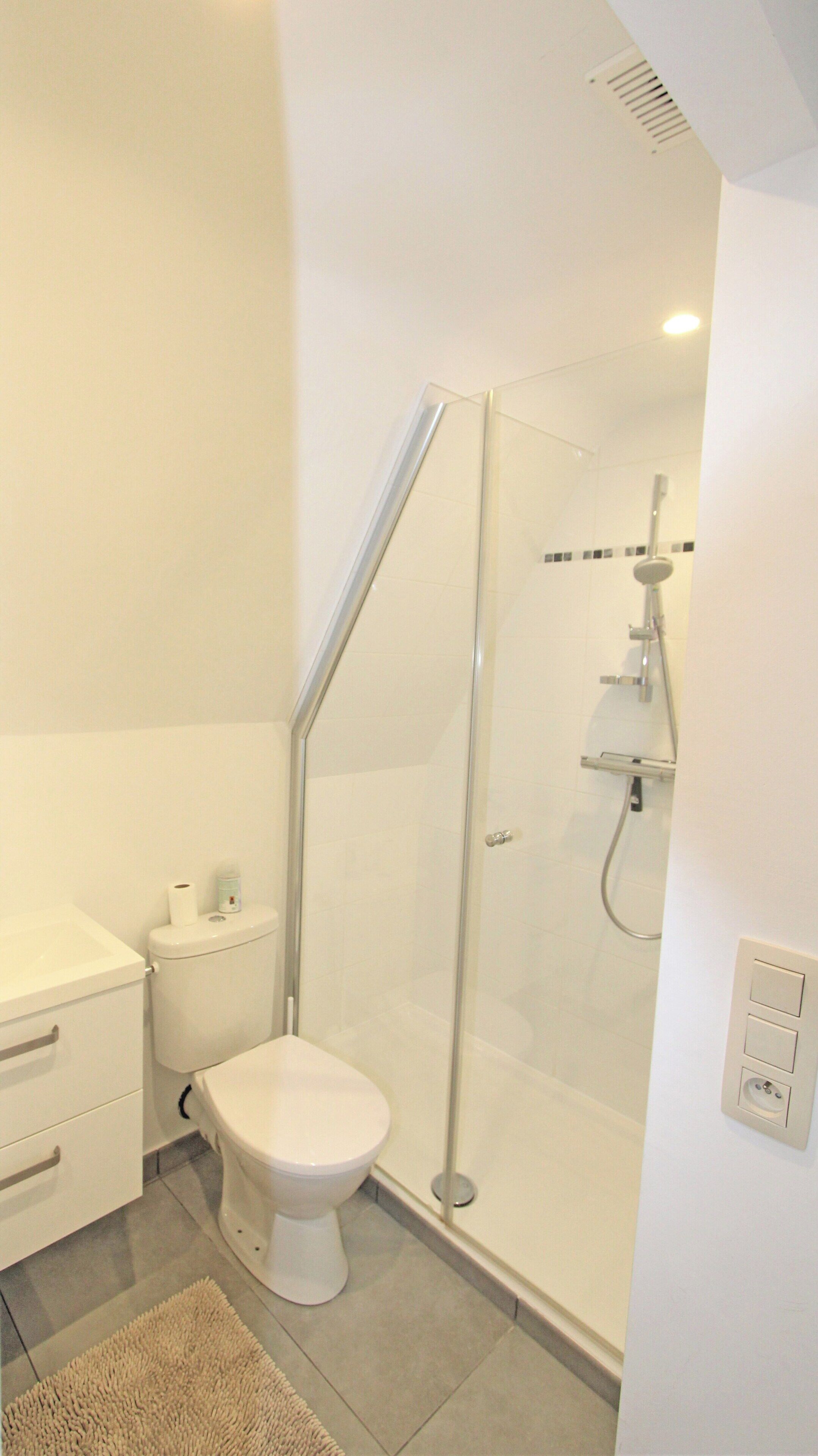 Un baño moderno con ducha de vidrio, inodoro y lavamanos.