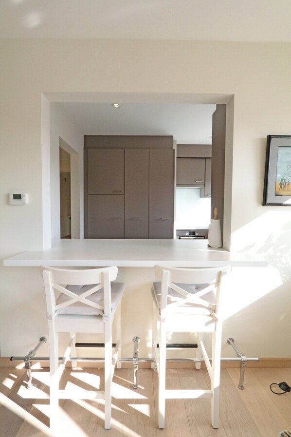 Een moderne keuken met een wit aanrecht en twee witte stoelen.