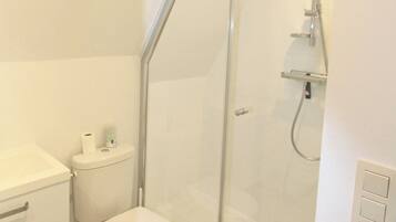 Un baño moderno con ducha de vidrio, inodoro y lavamanos.