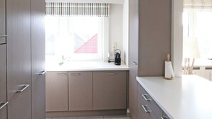 A modern kitchen with grey cabinets, a white countertop, and a window with a striped valance. - Apartment in Knokke Near Zwin Reserve (Knokke-Heist)