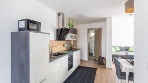 A modern kitchen with a microwave, oven, and sink. There is a dining area with a table and chairs. - Gemutliche Ferienwohnung, Beilngries (Beilngries)