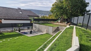 A residential backyard with a paved patio, a small play area, and a grassy lawn. - Gemutliche Ferienwohnung, Beilngries (Beilngries)
