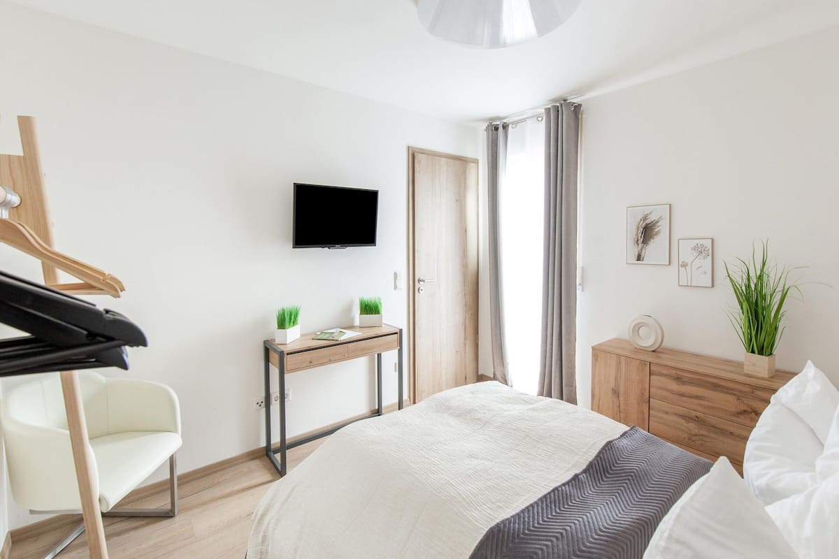 Ein Schlafzimmer mit einem Bett, einem Schreibtisch, einem Stuhl, einem Fernseher und einem Kleiderschrank.