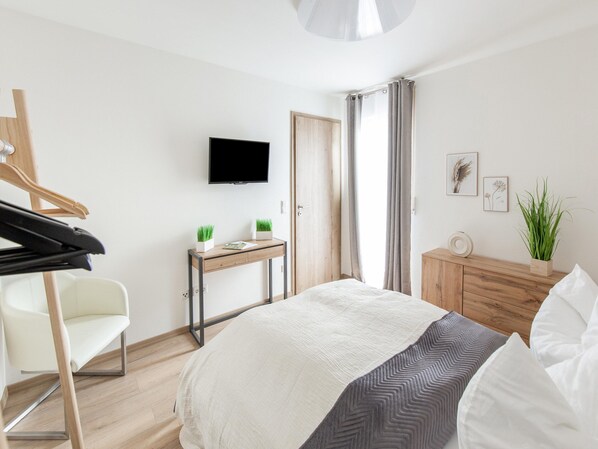 Un dormitorio con cama, escritorio, silla, televisor y armario.