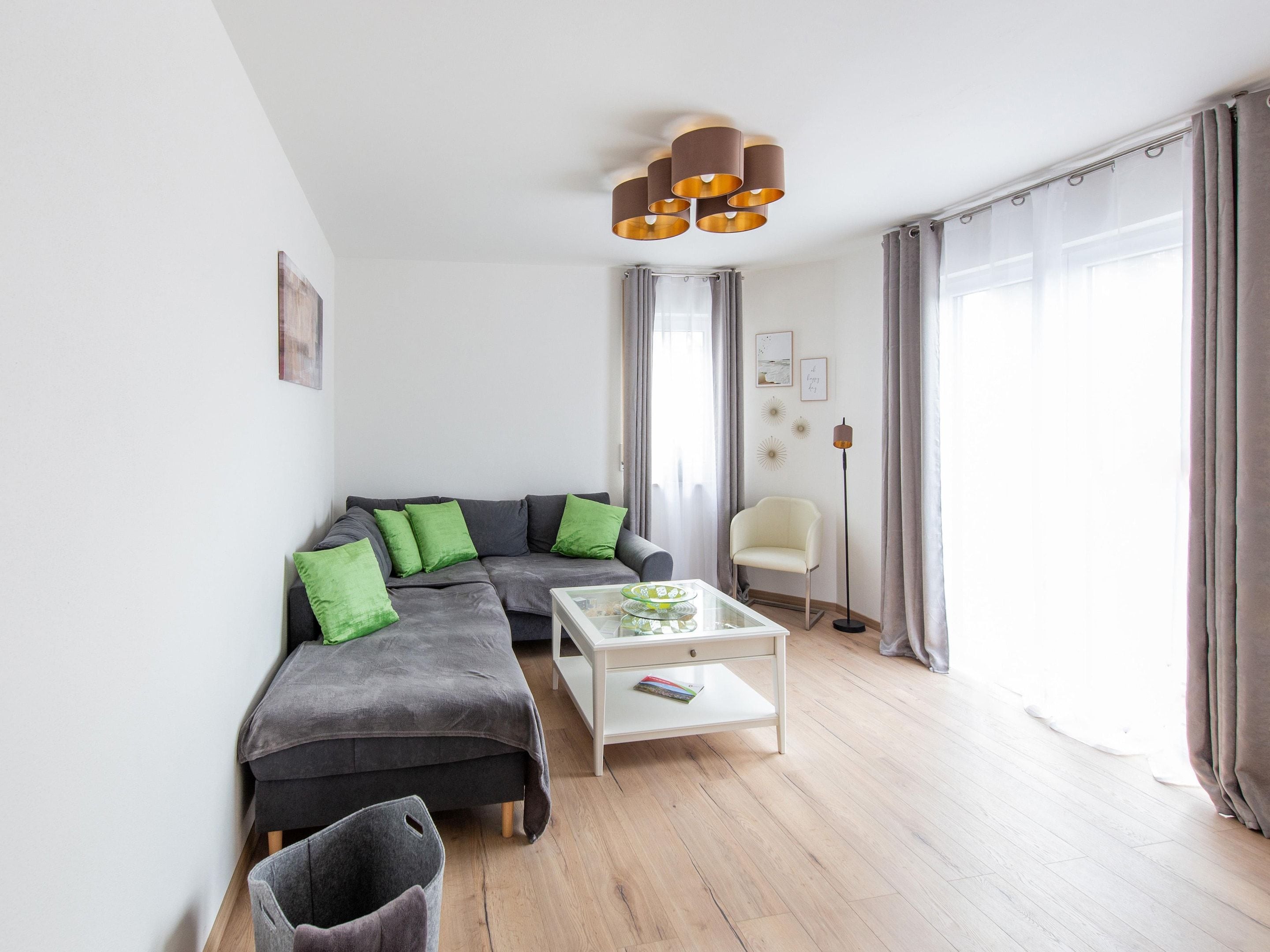 A modern living room with a grey sectional sofa, green cushions, a white coffee table, and a floor lamp.