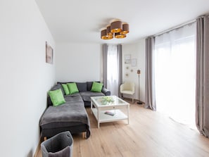 A modern living room with a grey sectional sofa, green cushions, a white coffee table, and a floor lamp. - Gemutliche Ferienwohnung, Beilngries (Beilngries)