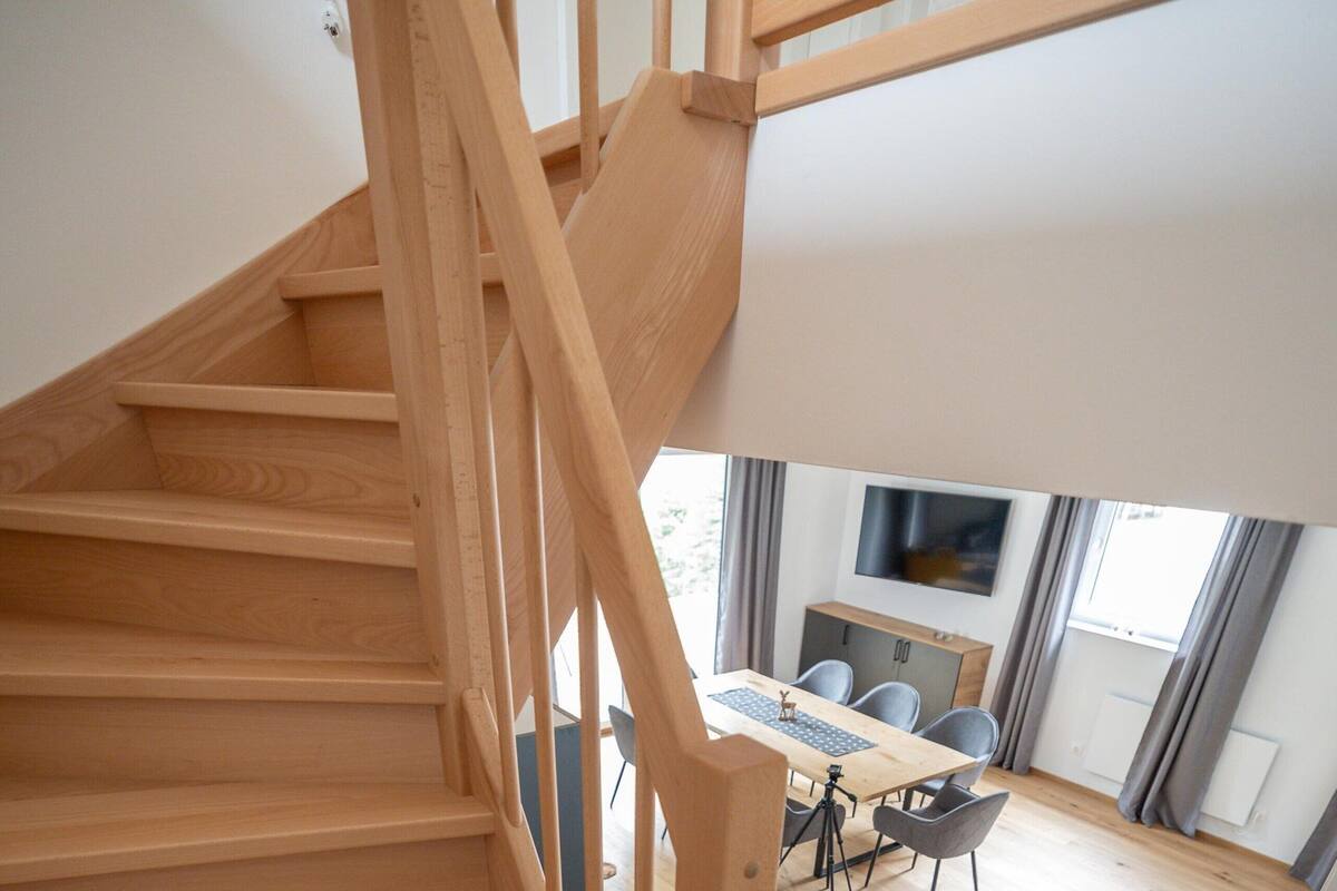 Una escalera de madera que conduce a un comedor con una mesa y sillas.