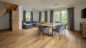 A modern living space with a dining area, sofa, and staircase. - Chalet in Turracher Hohe With Ski Slope Access (Reichenau)