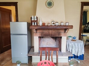 Eine Küche mit integriertem Kamin, einem Kühlschrank und einem Holzboden mit verschiedenen Küchenutensilien.