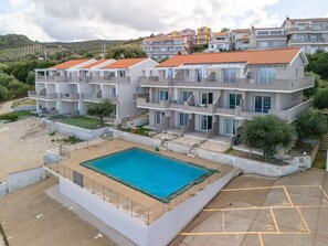 Ein mehrstöckiges Hotel mit Schwimmbad, Balkonen und Blick auf die Umgebung.