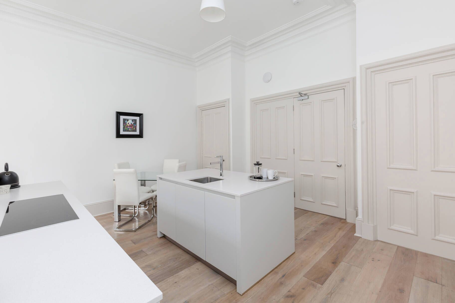 A modern kitchen with a central island, white cabinetry, and a dining area with a table and chairs.