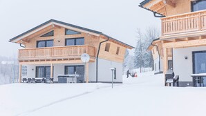 A wooden chalet with a balcony, outdoor seating, and a snow-covered landscape. - Chalet in St. Englmar With Private Sauna & Hottub (Sankt Englmar)