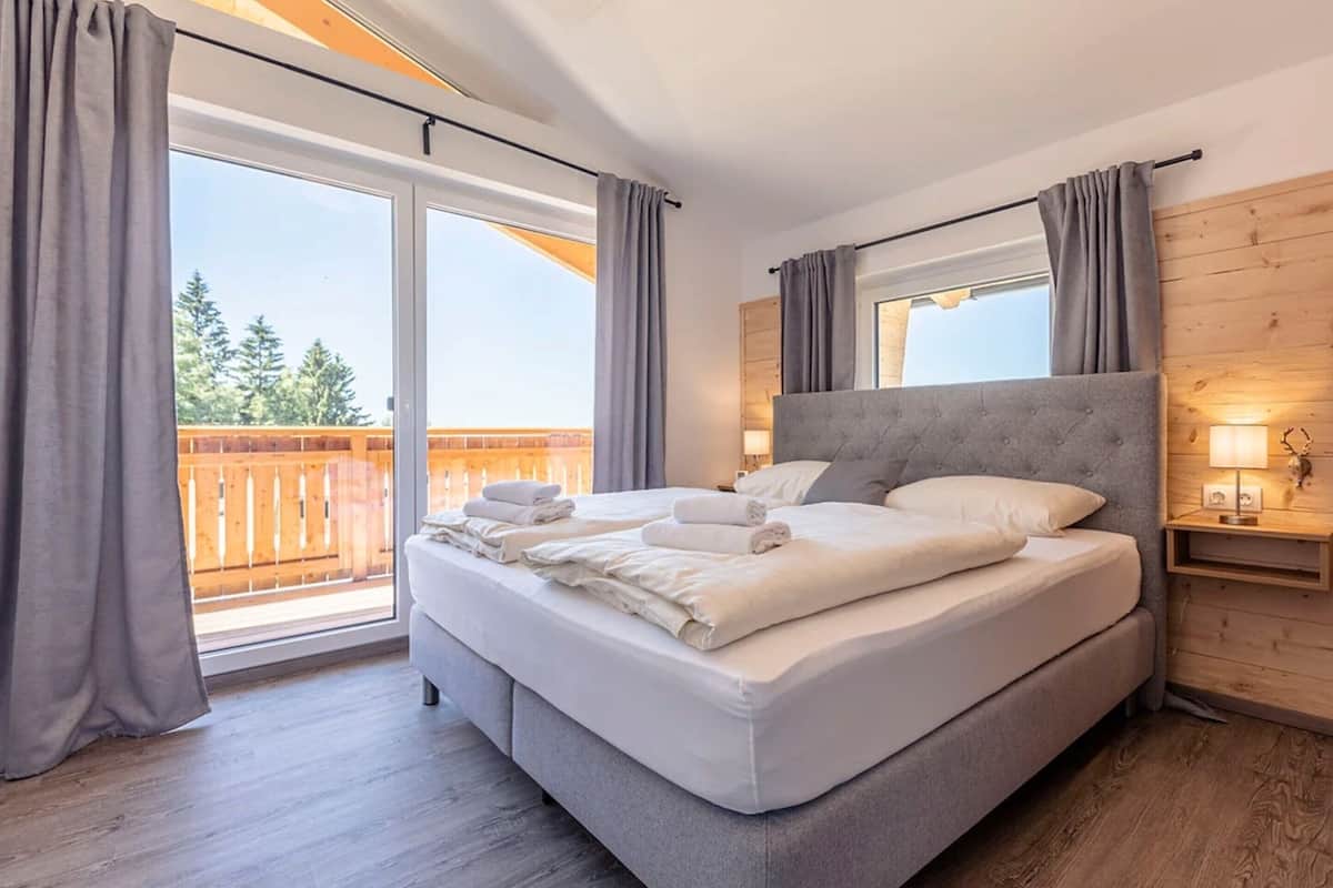 Ein Schlafzimmer mit einem großen Bett, Holzboden, einem Balkon mit Holzlatten und einer Holzwand.