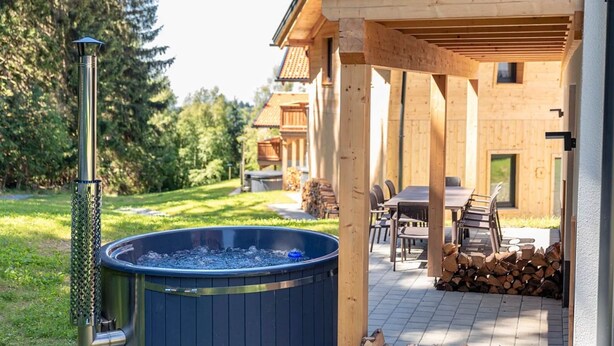 A wooden cabin with a hot tub, outdoor seating, and a covered patio area. - Chalet in St. Englmar With Private Sauna & Hottub (Sankt Englmar)