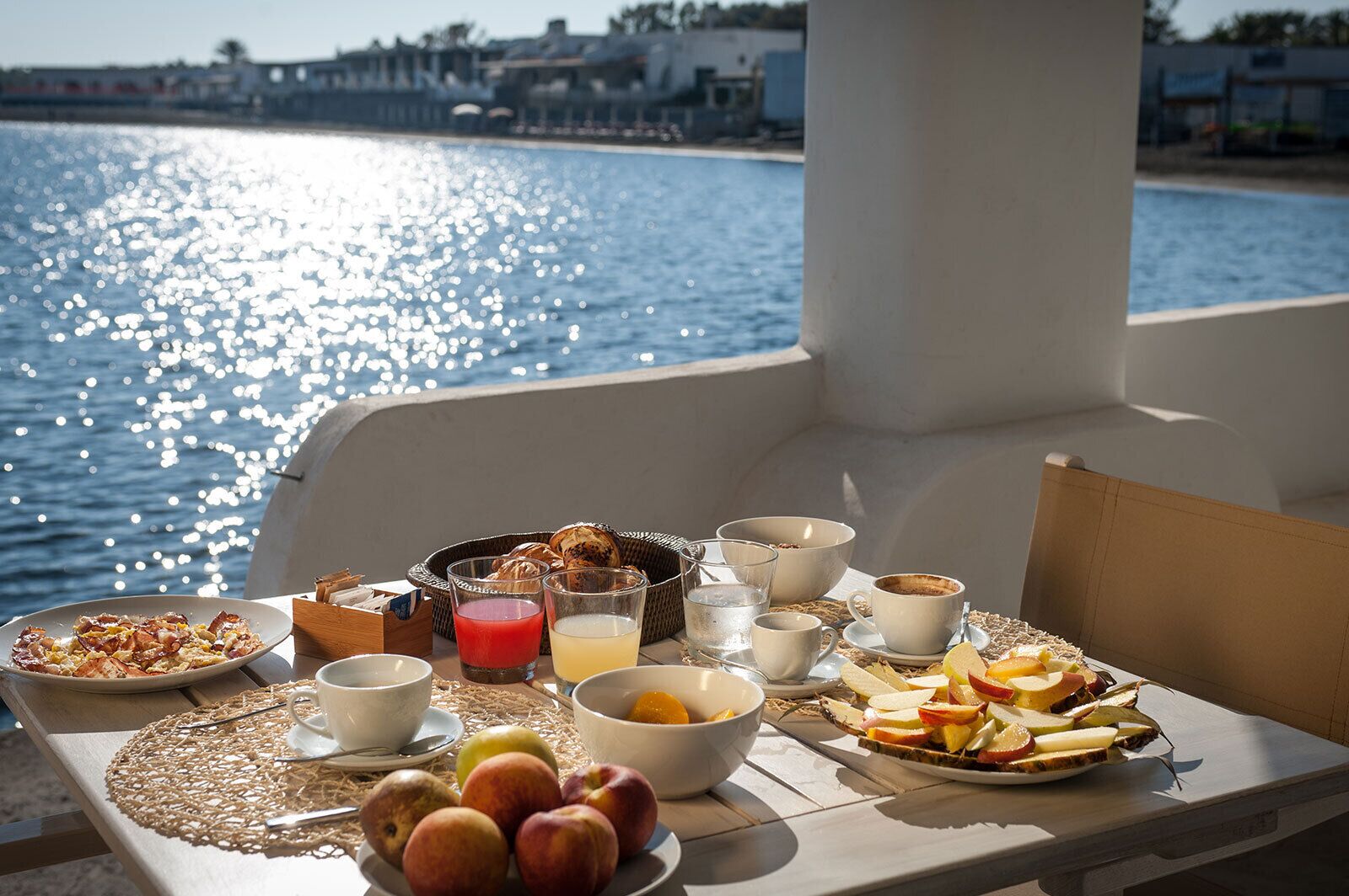 A table with breakfast items and a view of the sea.