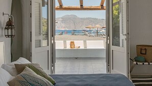 A bedroom with an open door leading to a balcony with a view of the sea and boats. - Life Resort Mari del Sud I Vulcano (Vulcano Porto)
