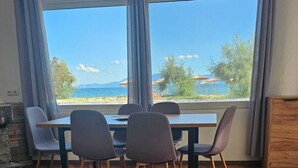Ein Zimmer mit Esstisch, vier Stühlen, einer Couch und Meerblick.