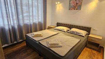 Un dormitorio con cama, suelo de madera, unidad de aire acondicionado, mesita de noche y un cuadro en la pared.