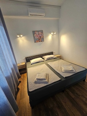 Une chambre avec un lit, un tableau et un appareil de climatisation.