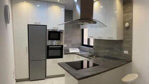 A modern kitchen with a central island, white cabinetry, and a stainless steel refrigerator.