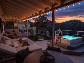 Eine Außenpatio mit Whirlpool, Sitzgruppe und Lichterketten.