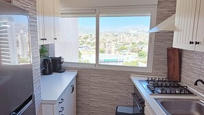A modern kitchen with a view of a cityscape, a coffee machine, and a gas stove. - Frontline Beach Penthouse ApoloXI Calpe (Calpe)