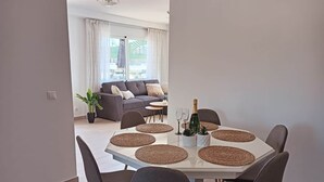 A dining area with a white table, grey chairs, and a bottle of champagne. - Frontline Beach Penthouse ApoloXI Calpe (Calpe)