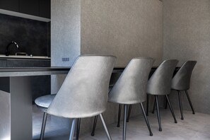 A modern kitchen with a dark countertop and four grey chairs with metal legs. - U suzukou (Asahikawa)