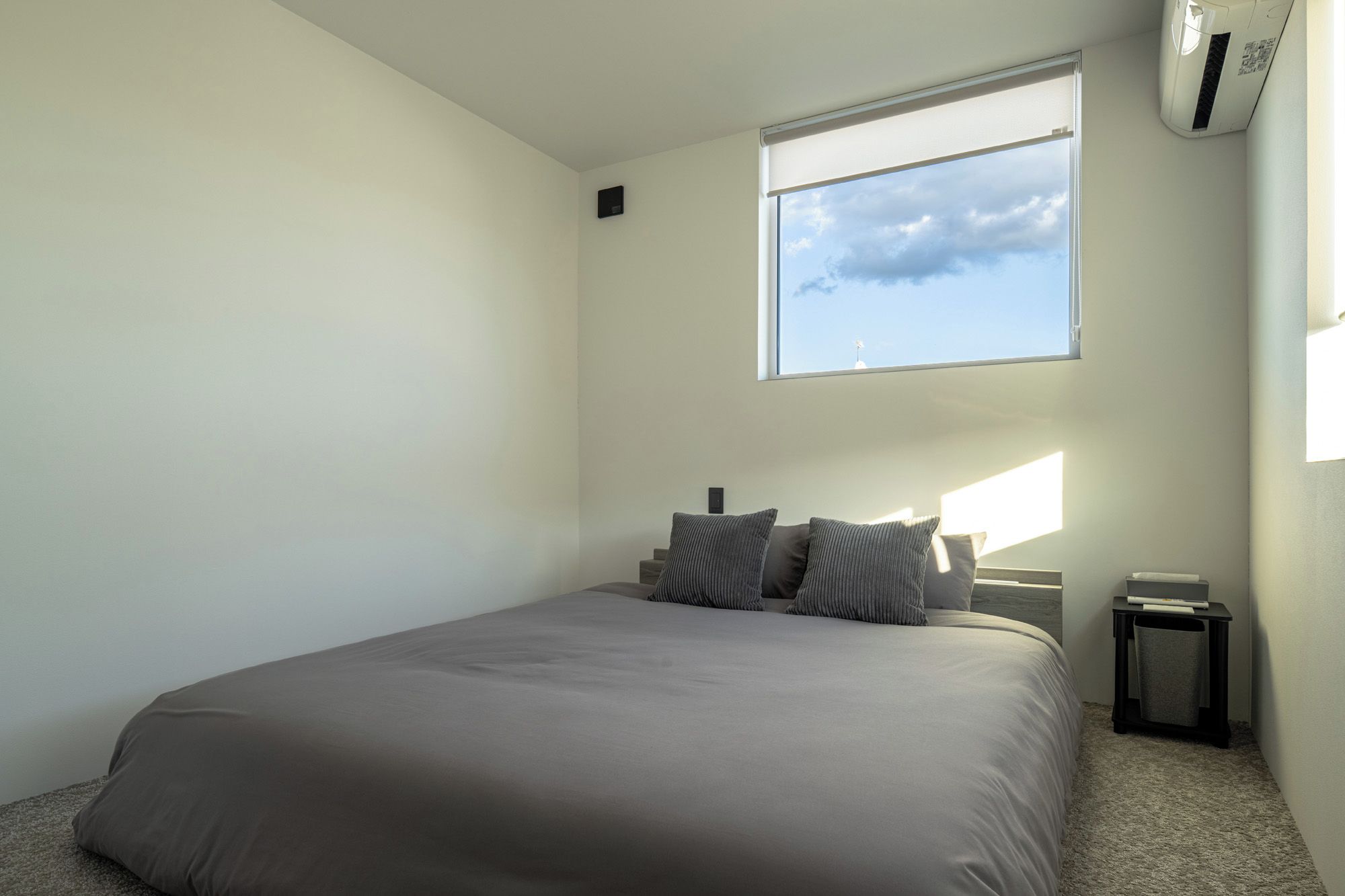 A bedroom with a bed, a window, and an air conditioning unit.