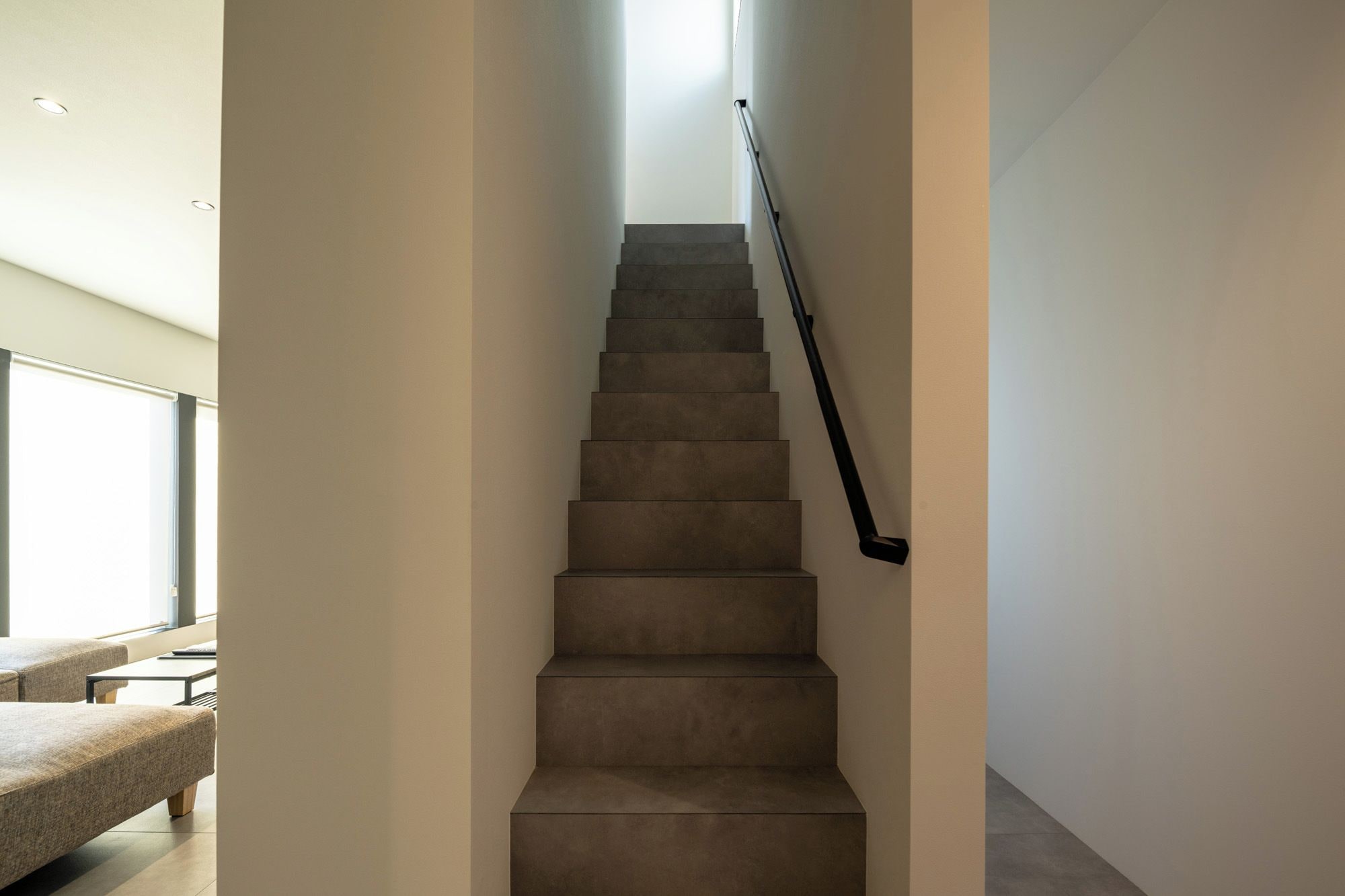 Una escalera con barandilla que lleva a un rellano con una ventana.