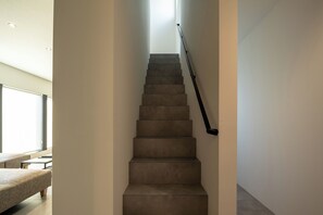 A staircase with a handrail, leading to a landing with a window. - U suzukoo (Asahikawa)