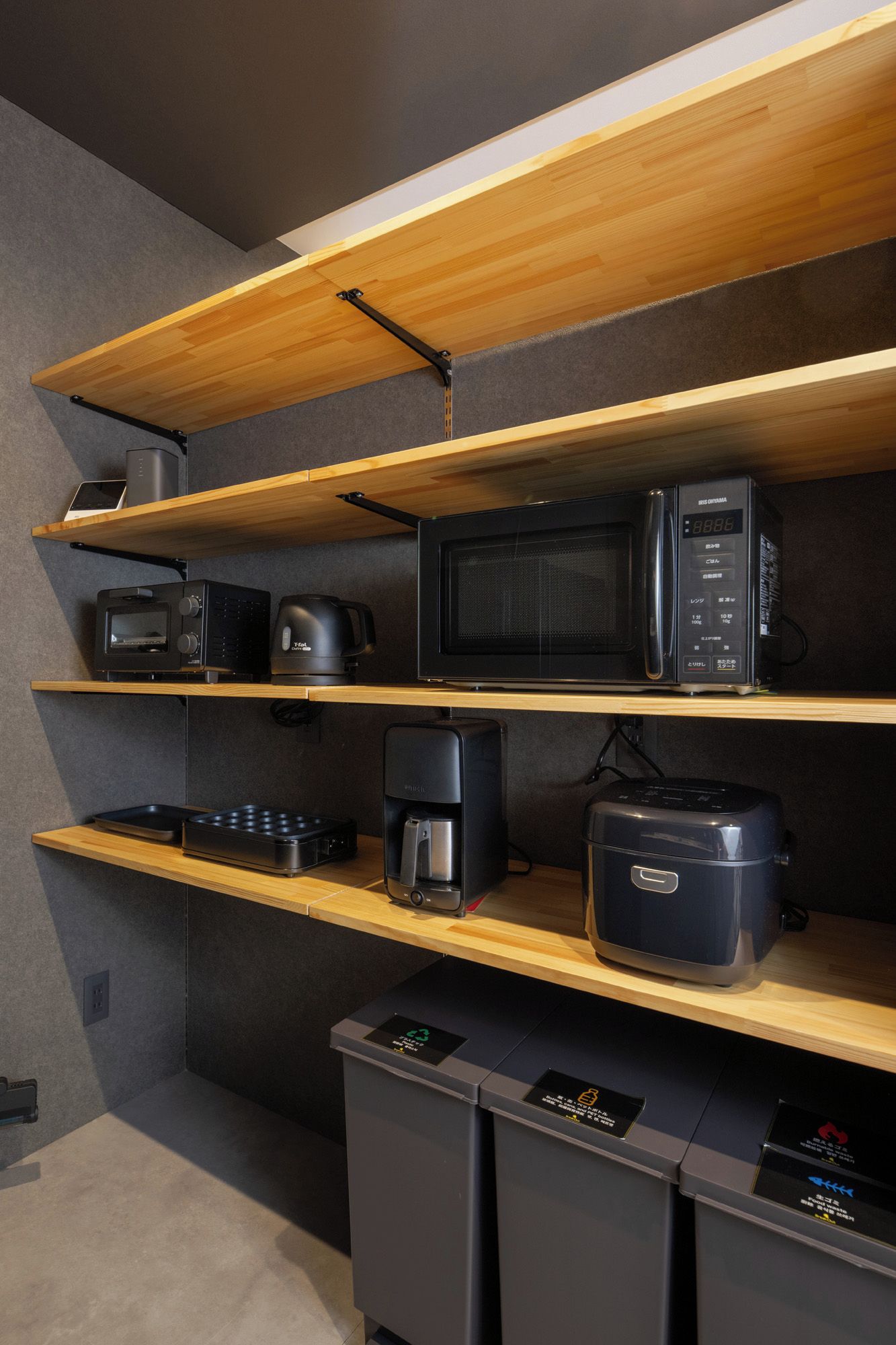 A kitchenette with wooden shelves, a microwave, a coffee maker, and a toaster.