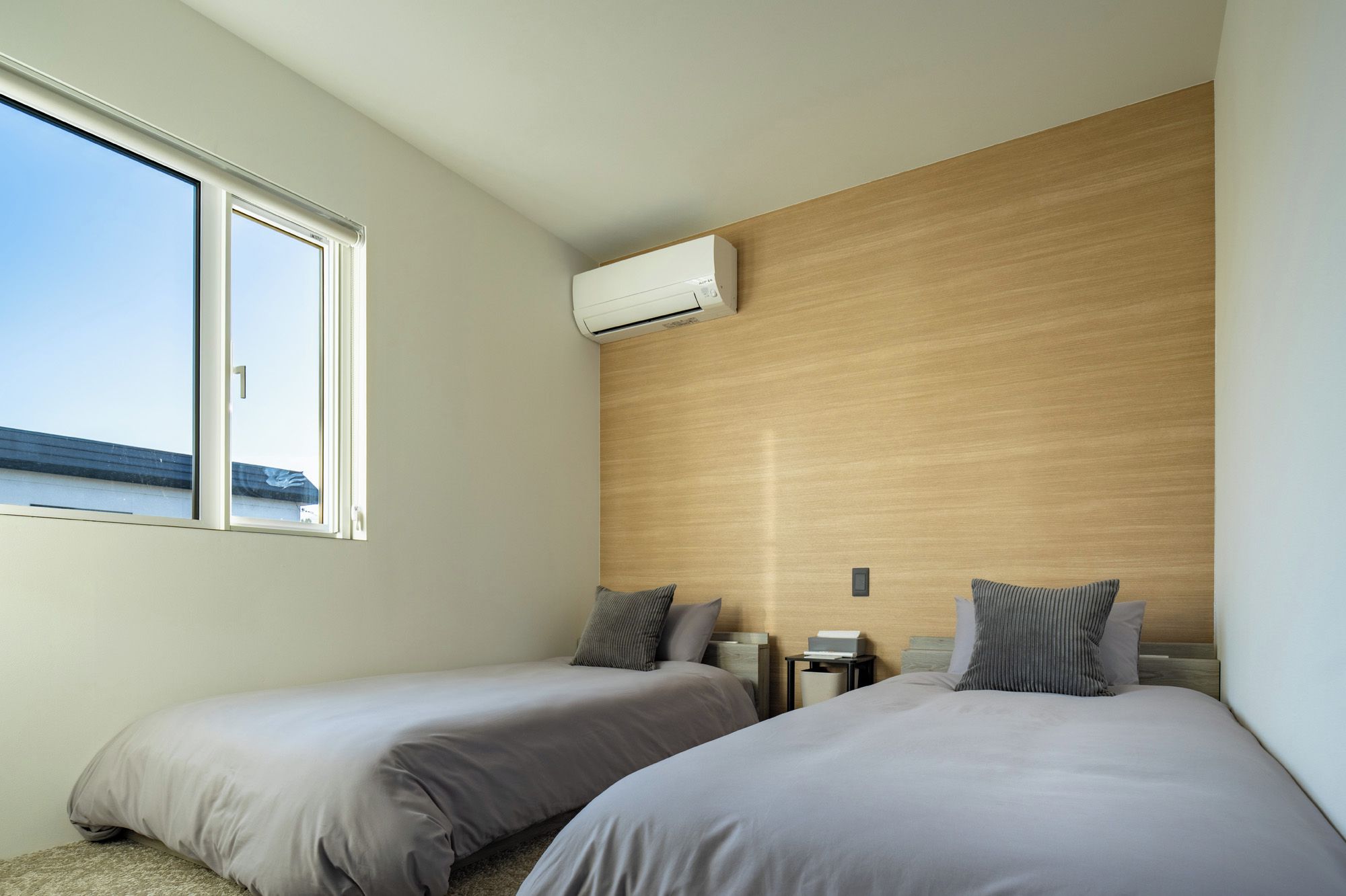 A bedroom with two beds, a window, and an air conditioning unit.