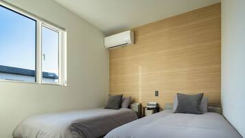 A bedroom with two beds, a window, and an air conditioning unit.
