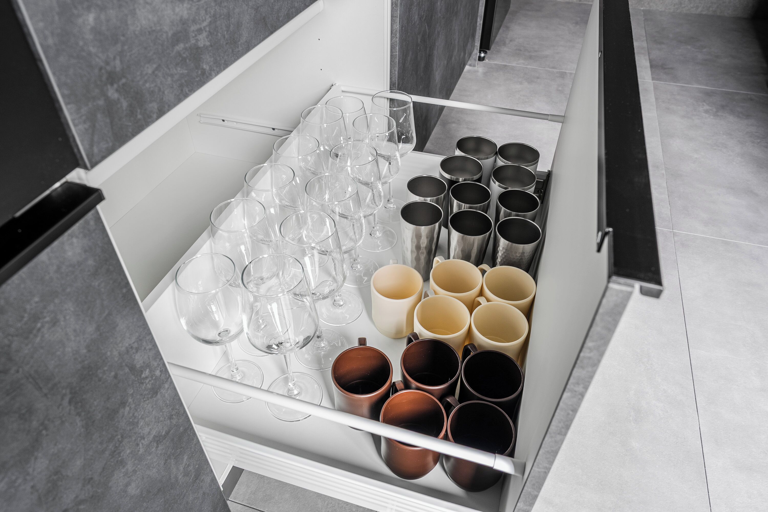 A drawer with wine glasses and mugs, indicating a setting with dining or beverage service.