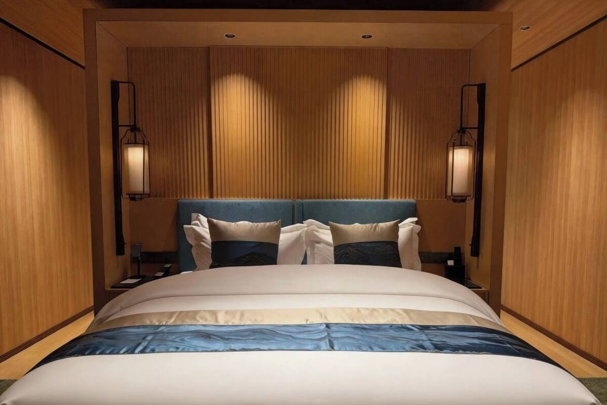 Een hotelkamer met een groot bed, twee bedlampen en houten lambrisering.