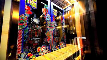 A window display with Martini Cognac bottles, colorful artwork, and a wooden bench.