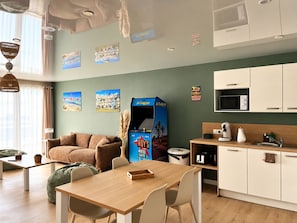 A modern room with a sofa, a wooden table, a kitchenette, and wall art. - San Francisco - Apartment in a complex with a pool (Neuf-Mesnil)