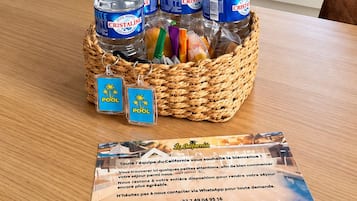 Una cocina con armarios blancos, microondas y ventana con vista a palmeras.